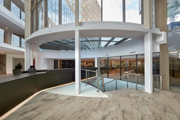 Moderne ontvangsthal aan de Fascinatio Boulevard met balie, glazen dak en zicht op een benedenverdieping.